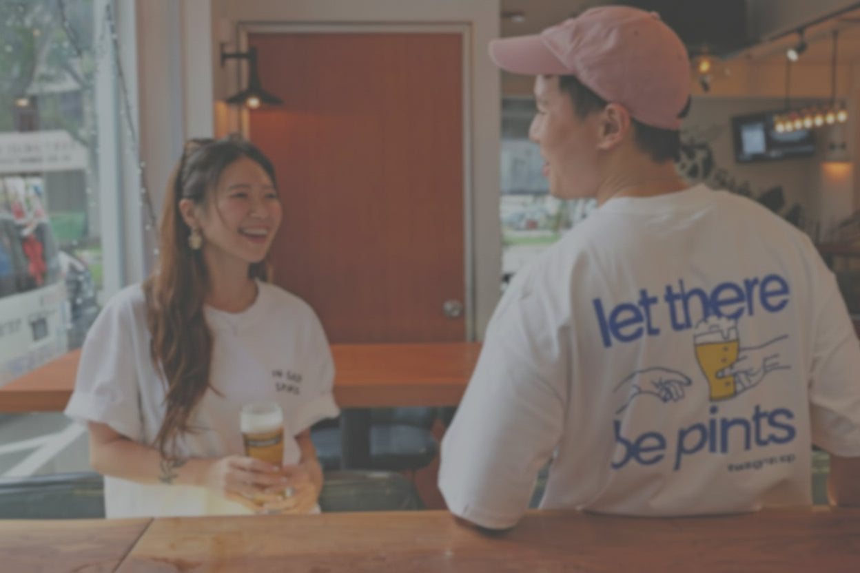 Two people sitting at a bar talking and laughing, both wearing ToT t-shirts.

